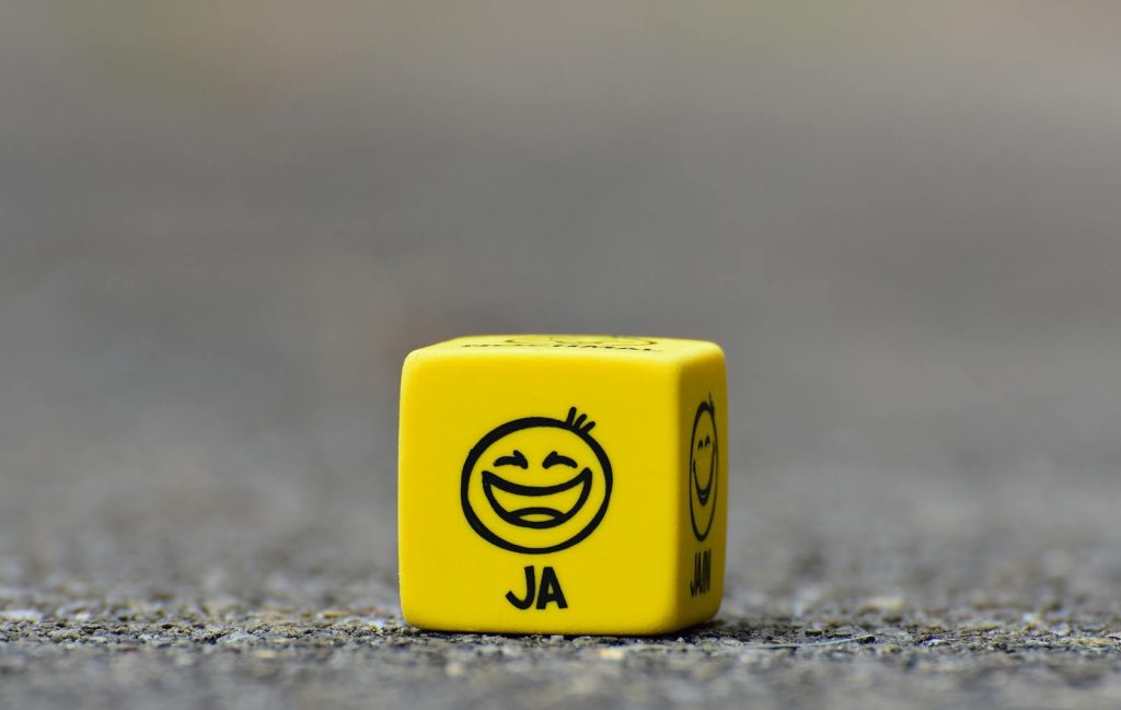 Close-up of a yellow dice featuring a smiley face emoticon symbolizing happiness and fun.