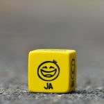 Close-up of a yellow dice featuring a smiley face emoticon symbolizing happiness and fun.