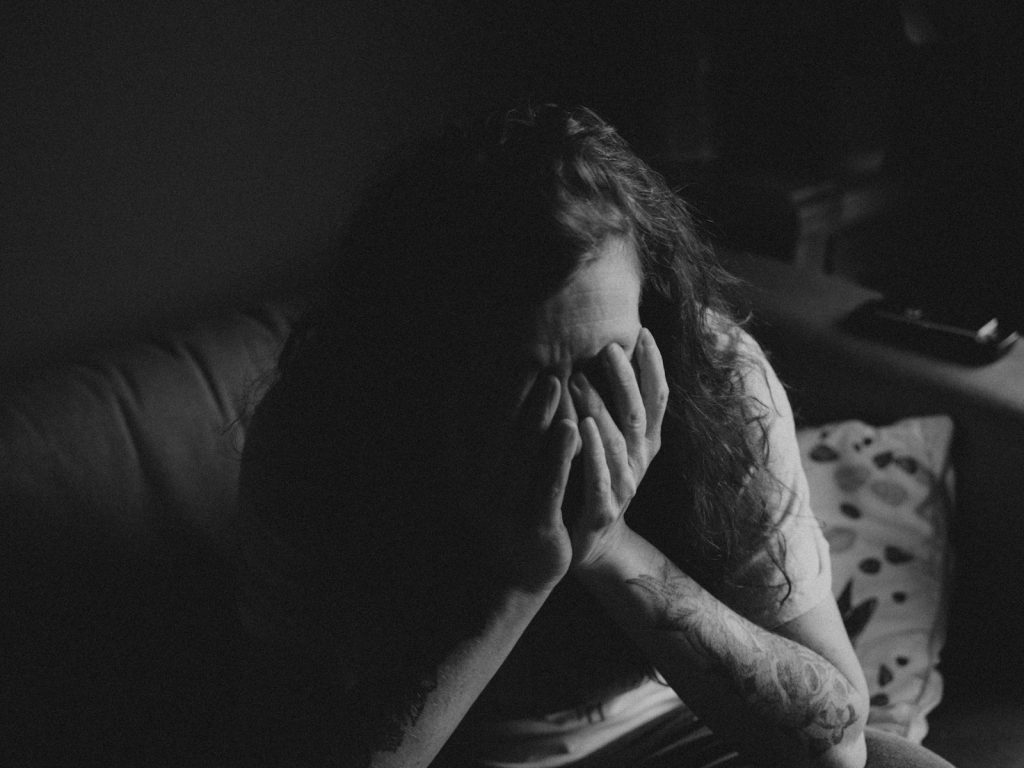 grayscale photo of woman covering face with her hands